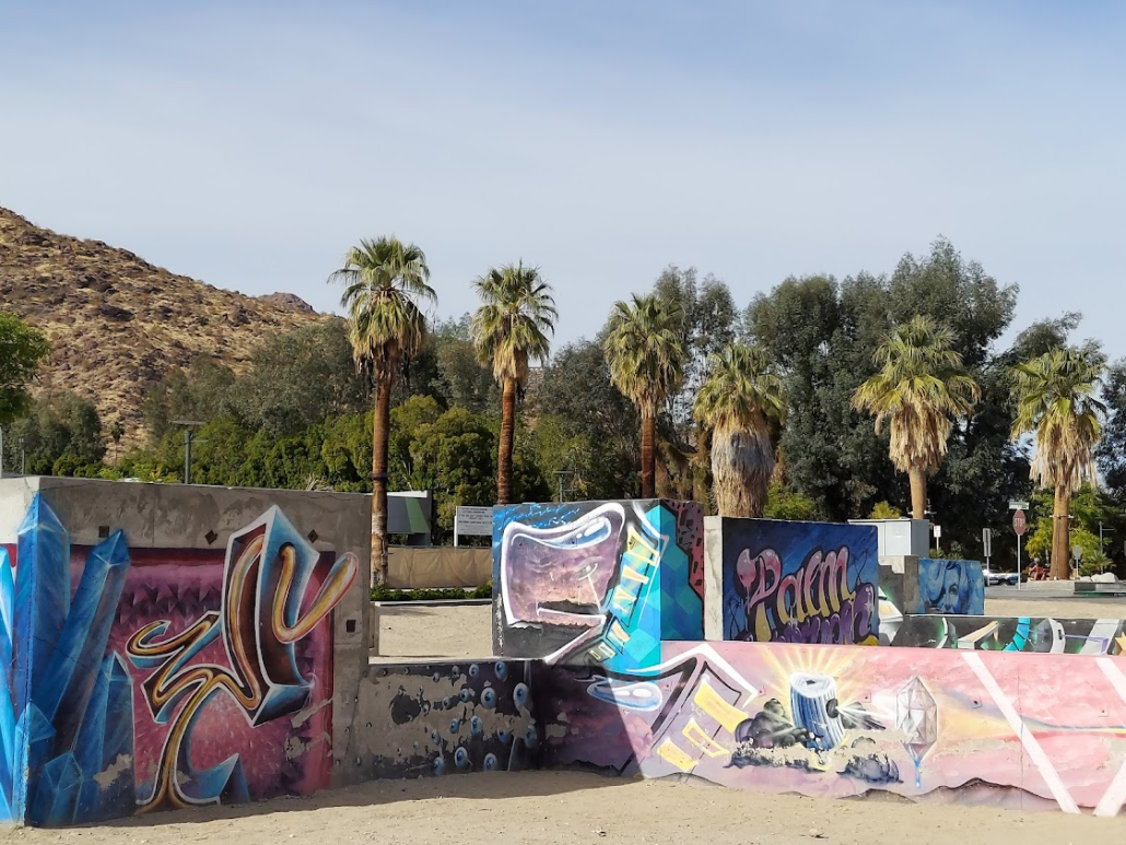 Graffiti on concrete barriers with palm trees in the background at the Graffiti Park in Palm Springs, California