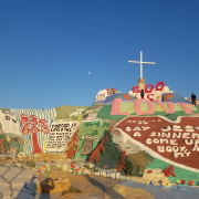 Paint on a rock and a giant cross on the top of Salvation Mountain