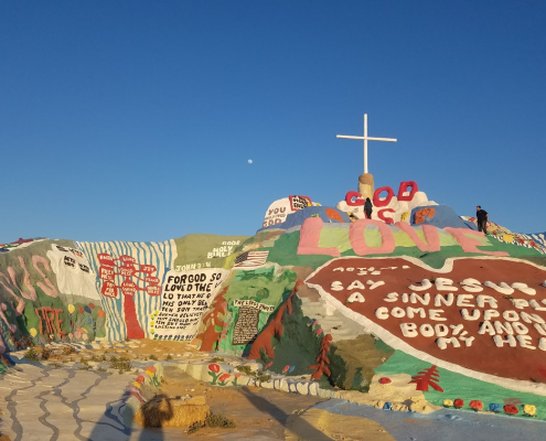 Paint on a rock and a giant cross on the top of Salvation Mountain