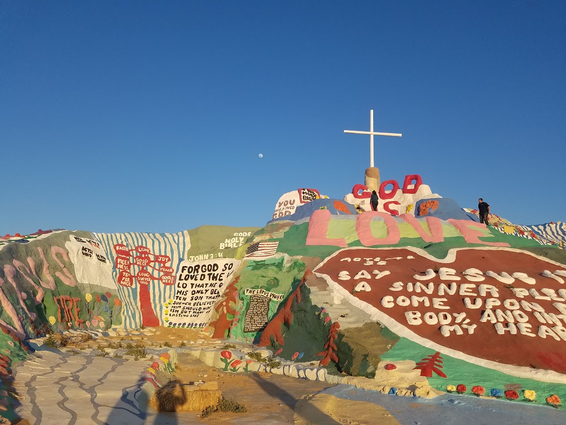 Paint on a rock and a giant cross on the top of Salvation Mountain