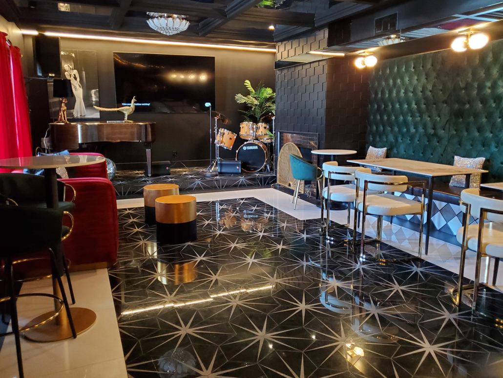 Starburst tiles on the floor of The Velvet Rope's Bar Valerie in Palm Springs, California, contrast with the deep red and green velvet walls and chairs