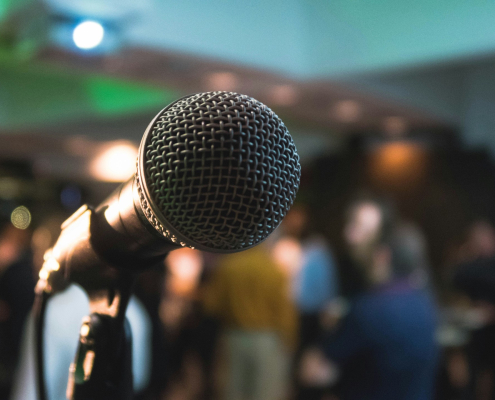 A microphone and stand on a stage with lights and people in the background