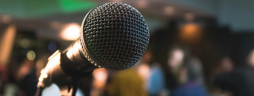 A microphone and stand on a stage with lights and people in the background