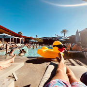 A man relaxes on a chaise lounge by the pool in Palm Springs, California, with a rubber duck float in the water