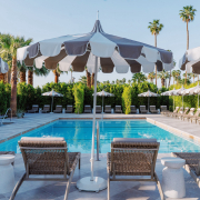 Four lounge chairs and striped umbrellas in front of the pool at Azure Sky Resort in Palm Springs, California