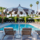 Four lounge chairs and striped umbrellas in front of the pool at Azure Sky Resort in Palm Springs, California