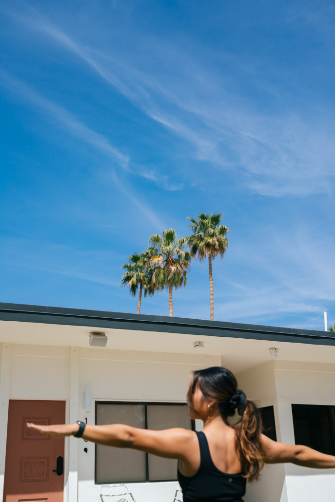 A woman with long dark hair practices yoga outside on a sunny day at the Azure Aky Resort in Palm Springs, California