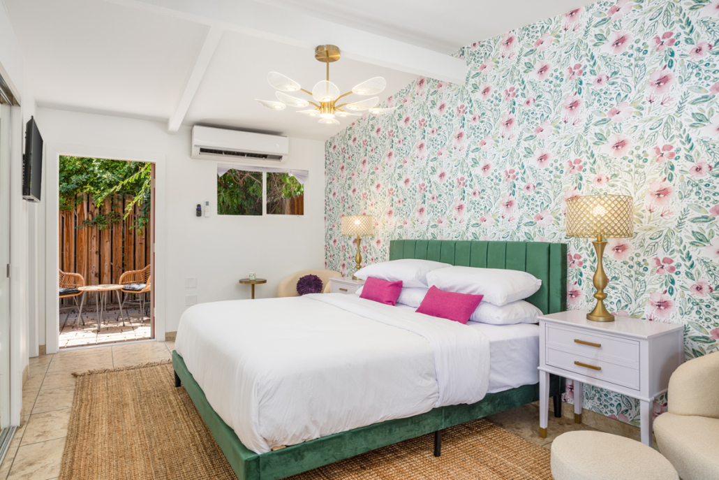 A white bed with a green headboard and pink pillows at The Muse Hotel in Palm Springs, California