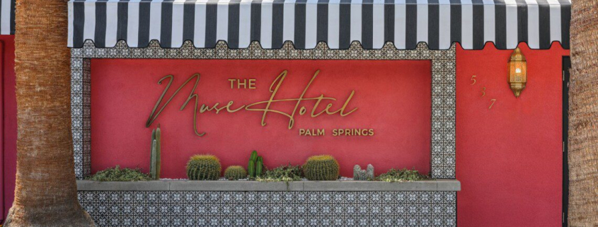 The front of The Muse Hotel Palm Springs is painted pink with a black and white striped awning