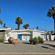 A white mid-century modern home in Palm Springs with a blue door