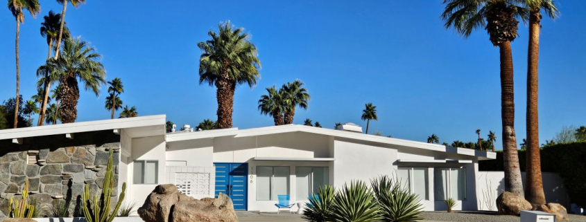 A white mid-century modern home in Palm Springs with a blue door