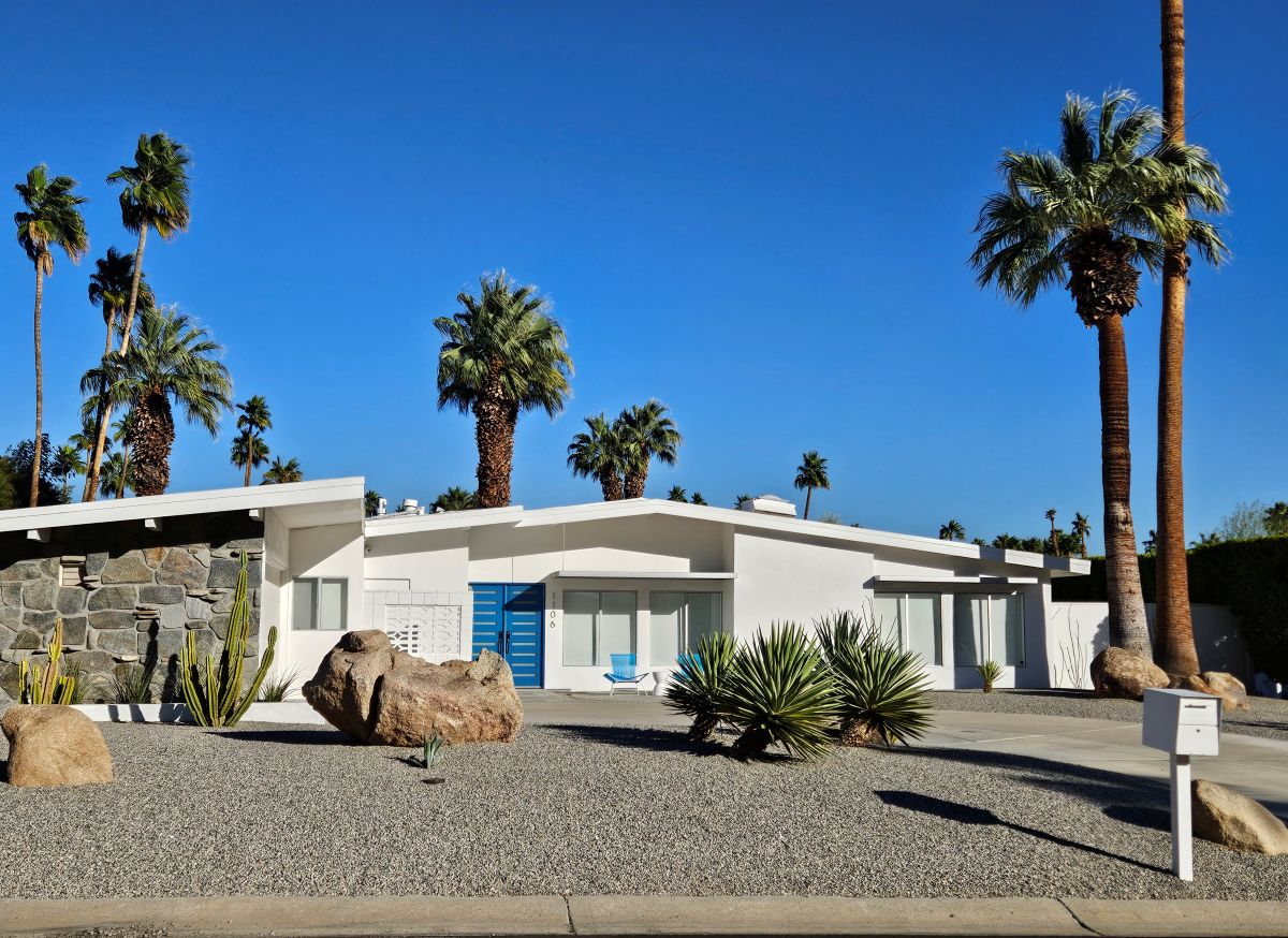 A white mid-century modern home in Palm Springs with a blue door