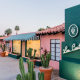 The front entrance to Les Cactus Palm Springs painted green and pink with cacti in pots