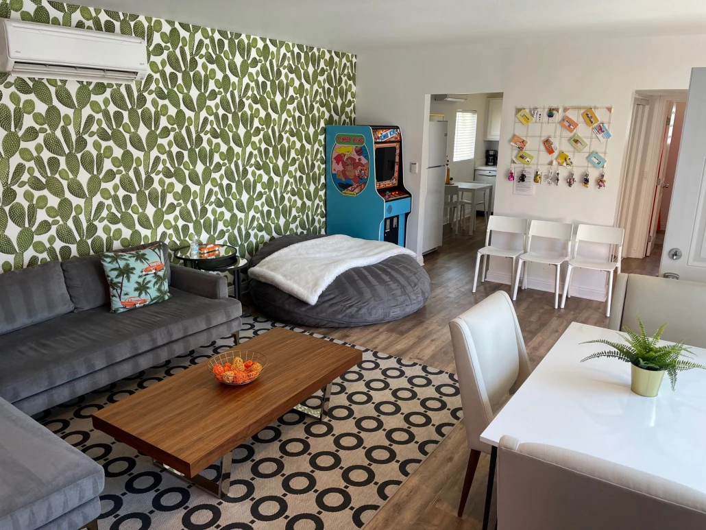 The living room space with a couch and arcade game at The Three Ten Hotel in Palm Springs