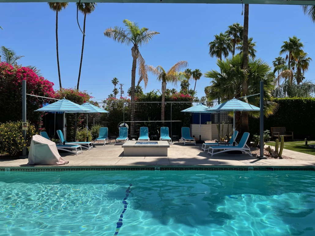 A pool surrounded by blue umbrellas and chairs